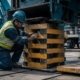 Construction workers building a properly configured box crib stack of composite cribbing blocks beneath heavy equipment at a construction site