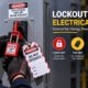 Worker applying lockout tagout on high voltage electrical panel with danger locked out do not operate padlock and hazard tag showing the lock out tag out verify and work safe steps